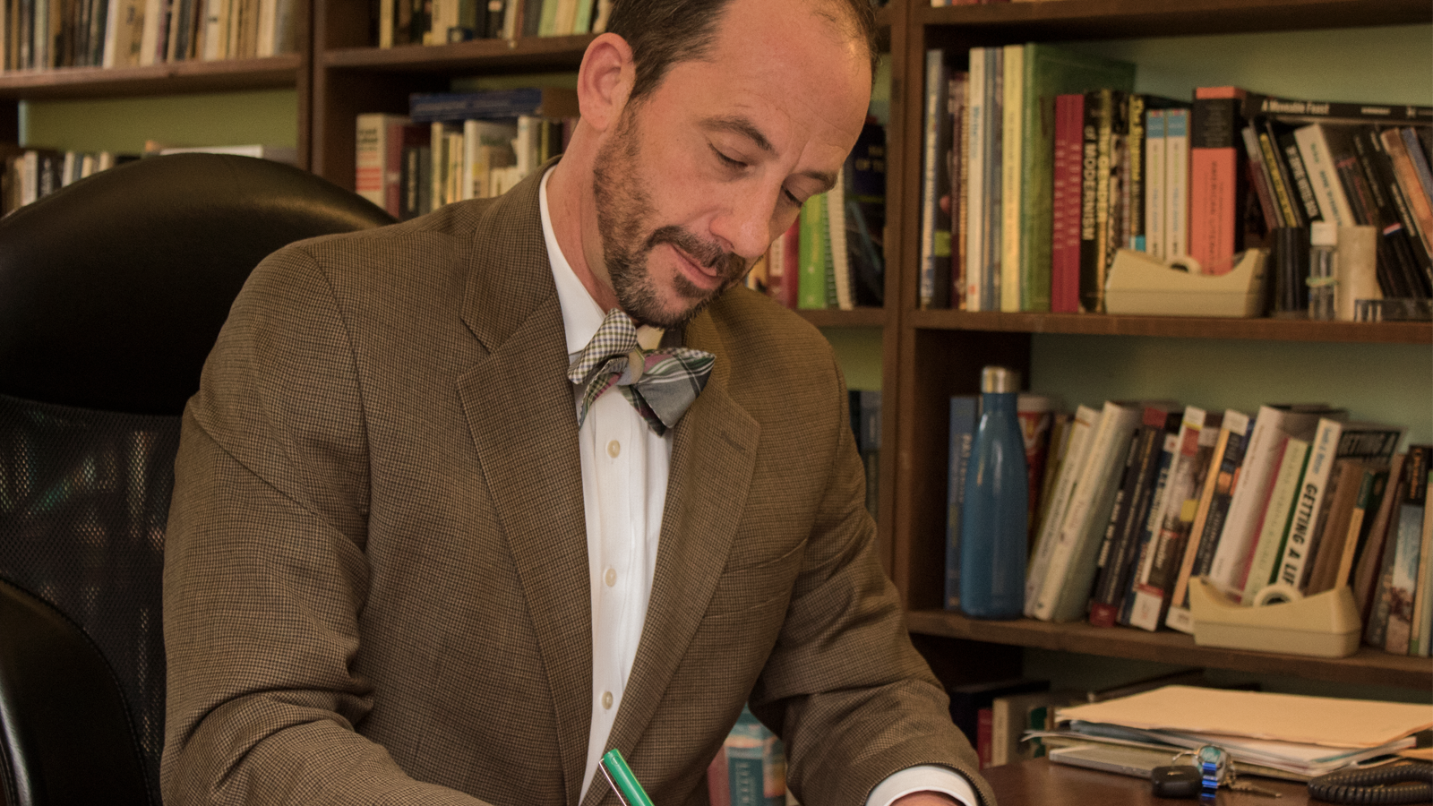 James Jaap reads Willa Cather in his office in front of book shelf