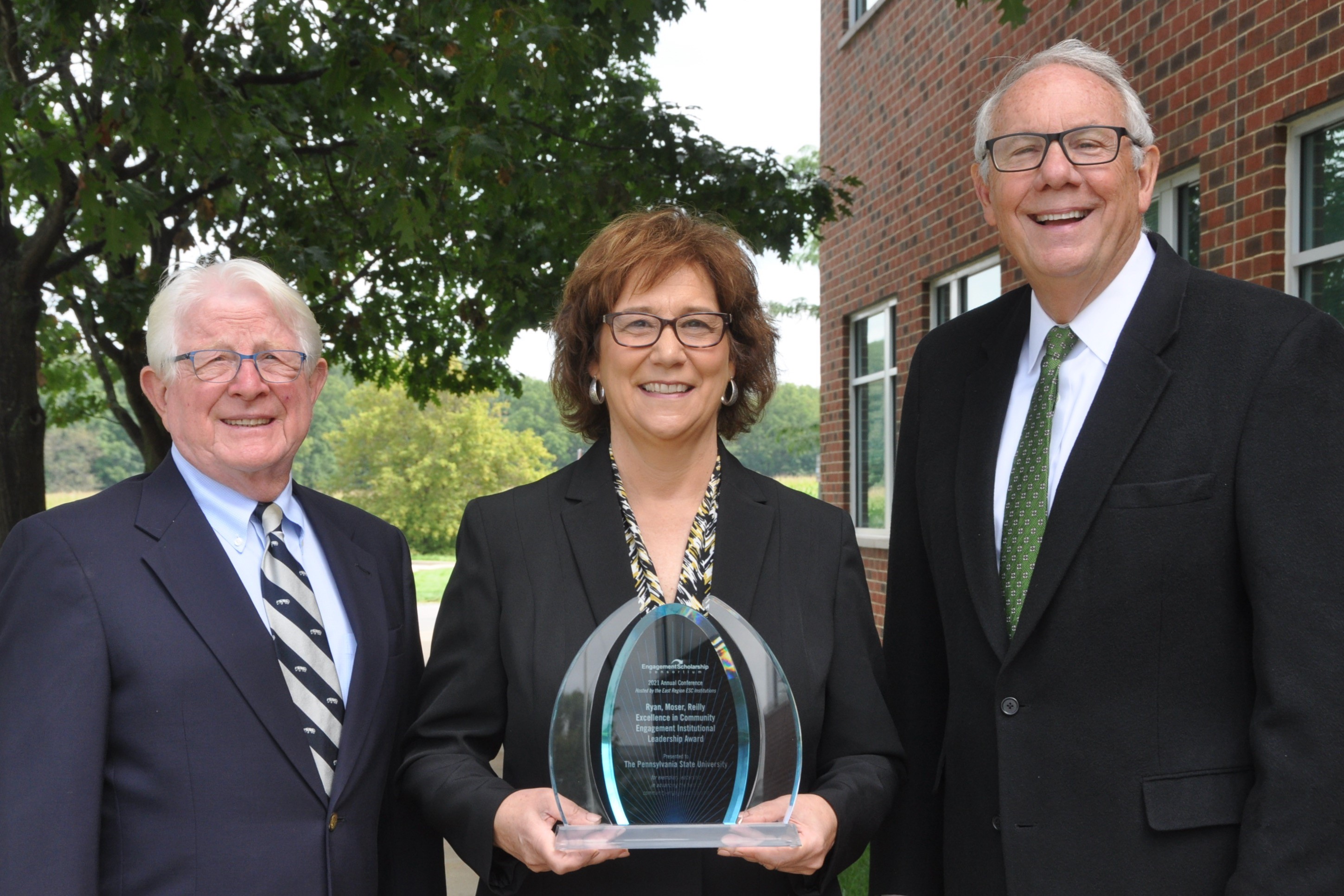 Portrait of award winners holding a plaque