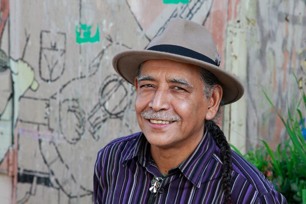 photo portrait of Jorge Argueta, man with mustache wearing hat and striped shirt