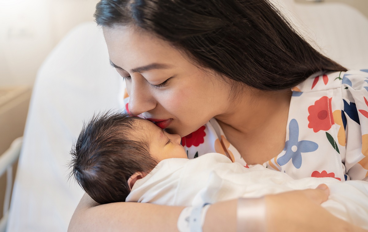 Close-up portrait of young mother holding newborn baby.