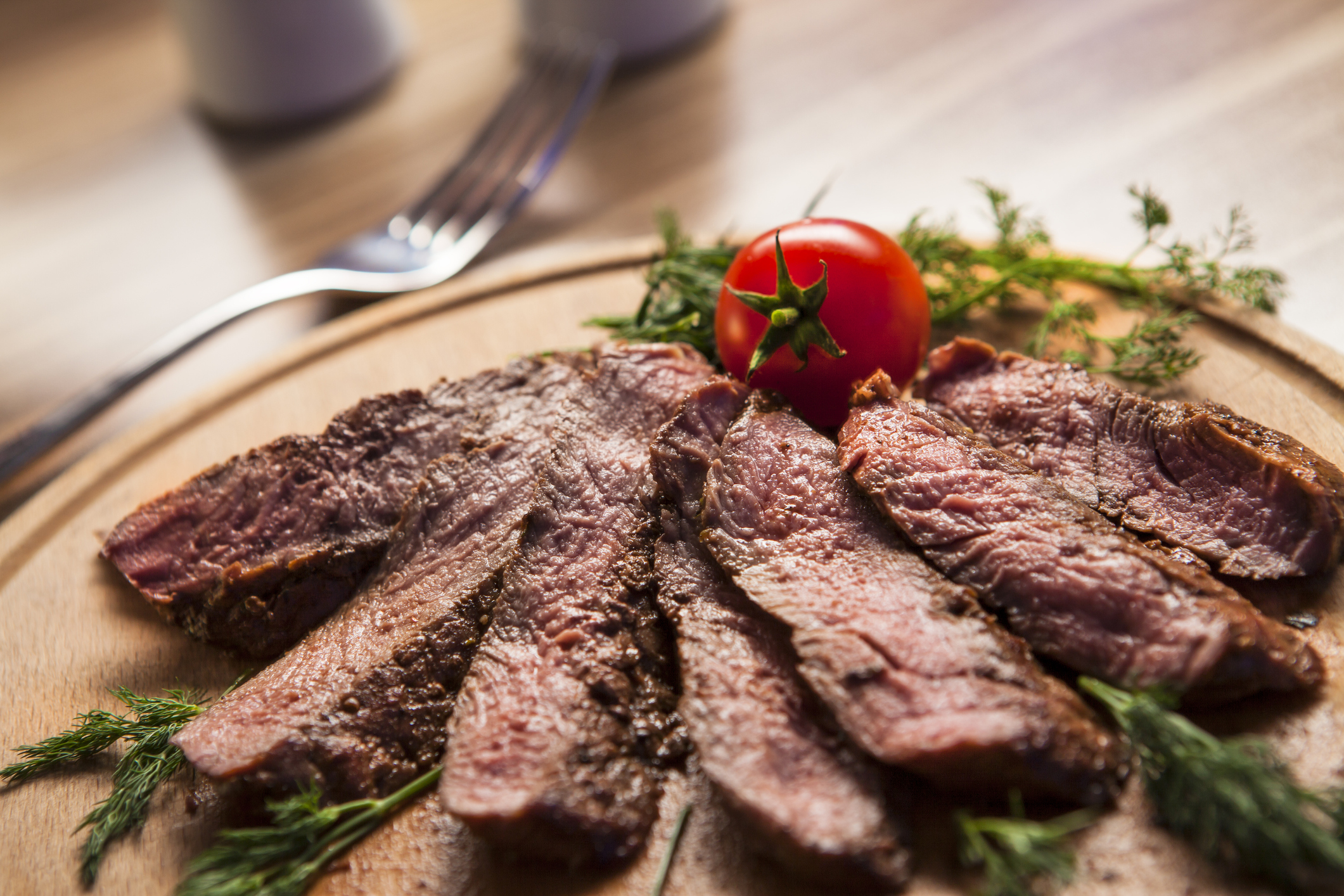 A plate of sliced beef garnished with a tomato