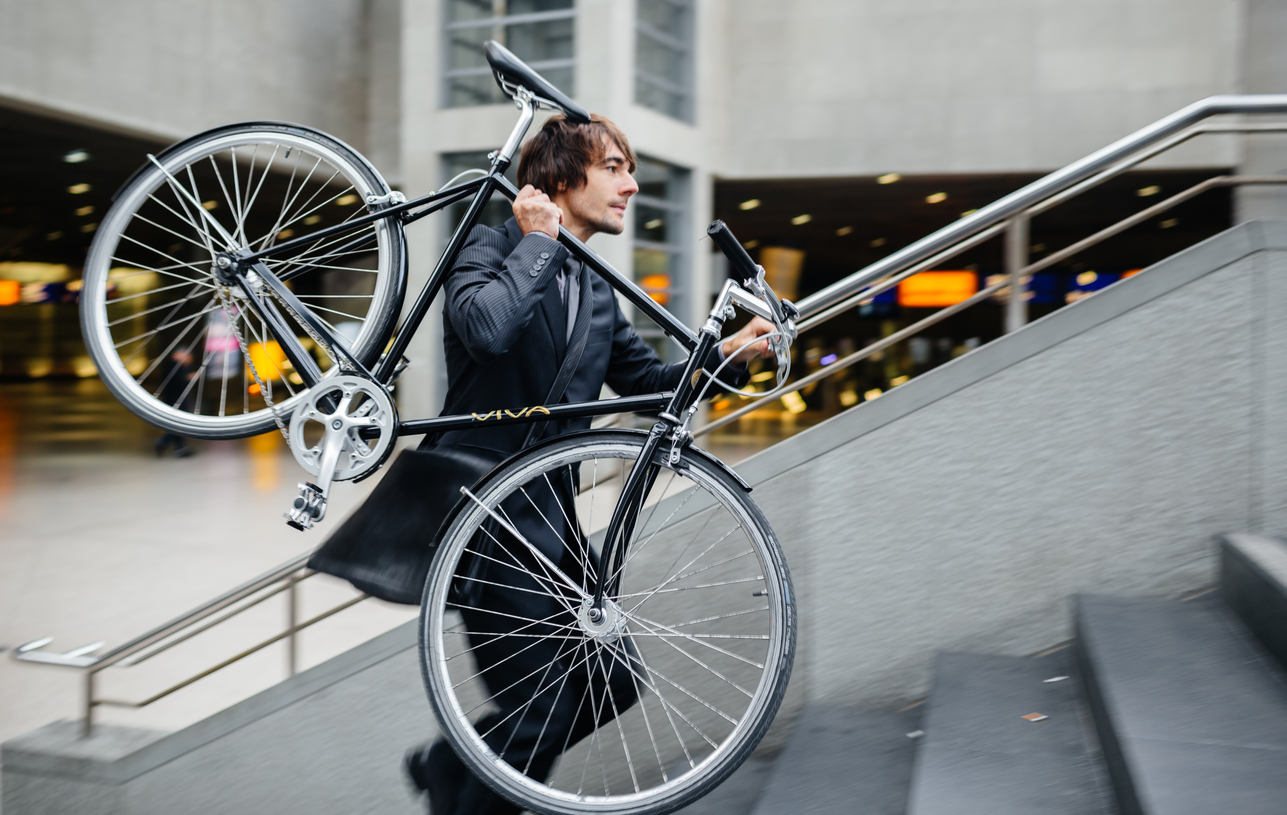 man in business suit carrying bike