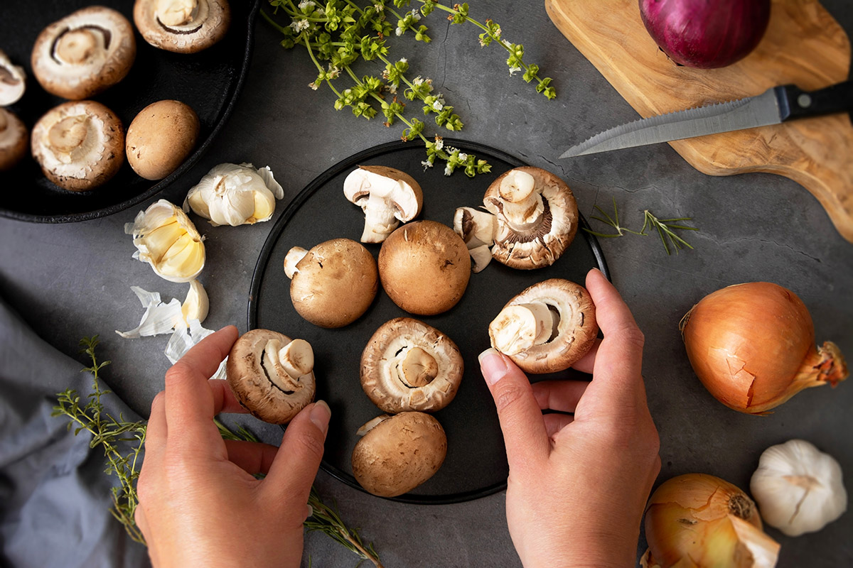 Two hands hold mushrooms that are ready to be prepared as part of a meal.