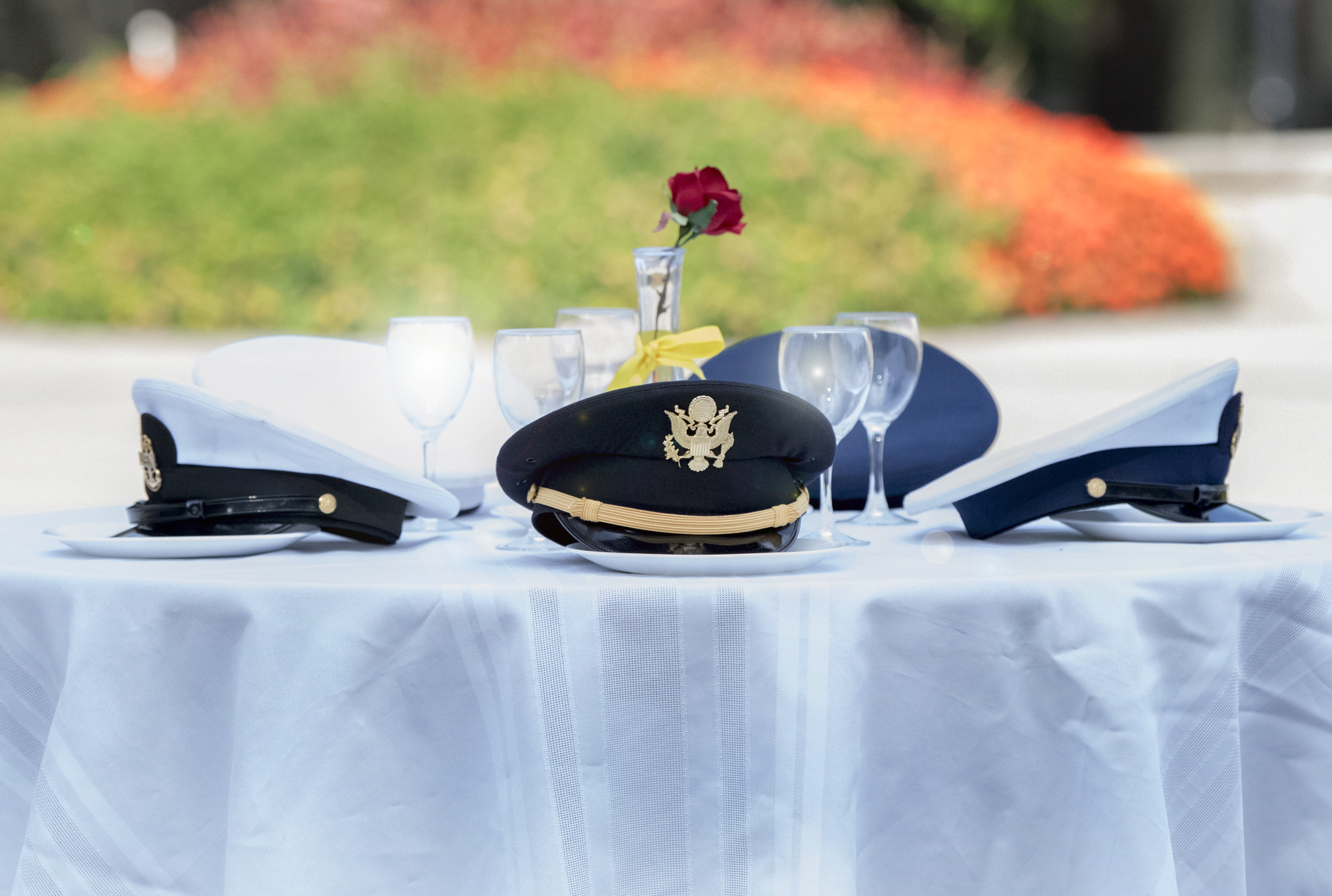 Hats from every military branch around an empty missing man table