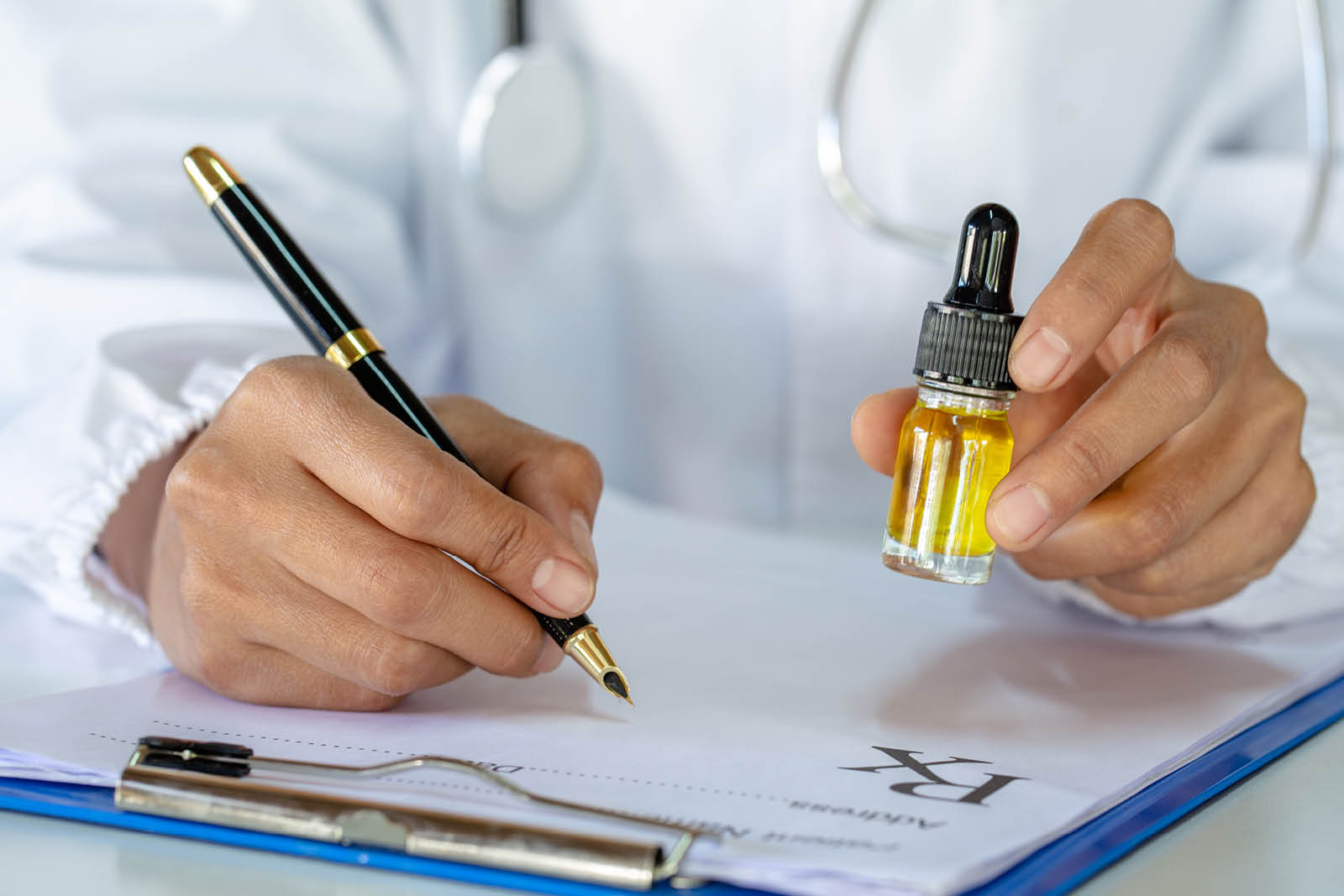 A person in a white doctor's coat writes on a clip board