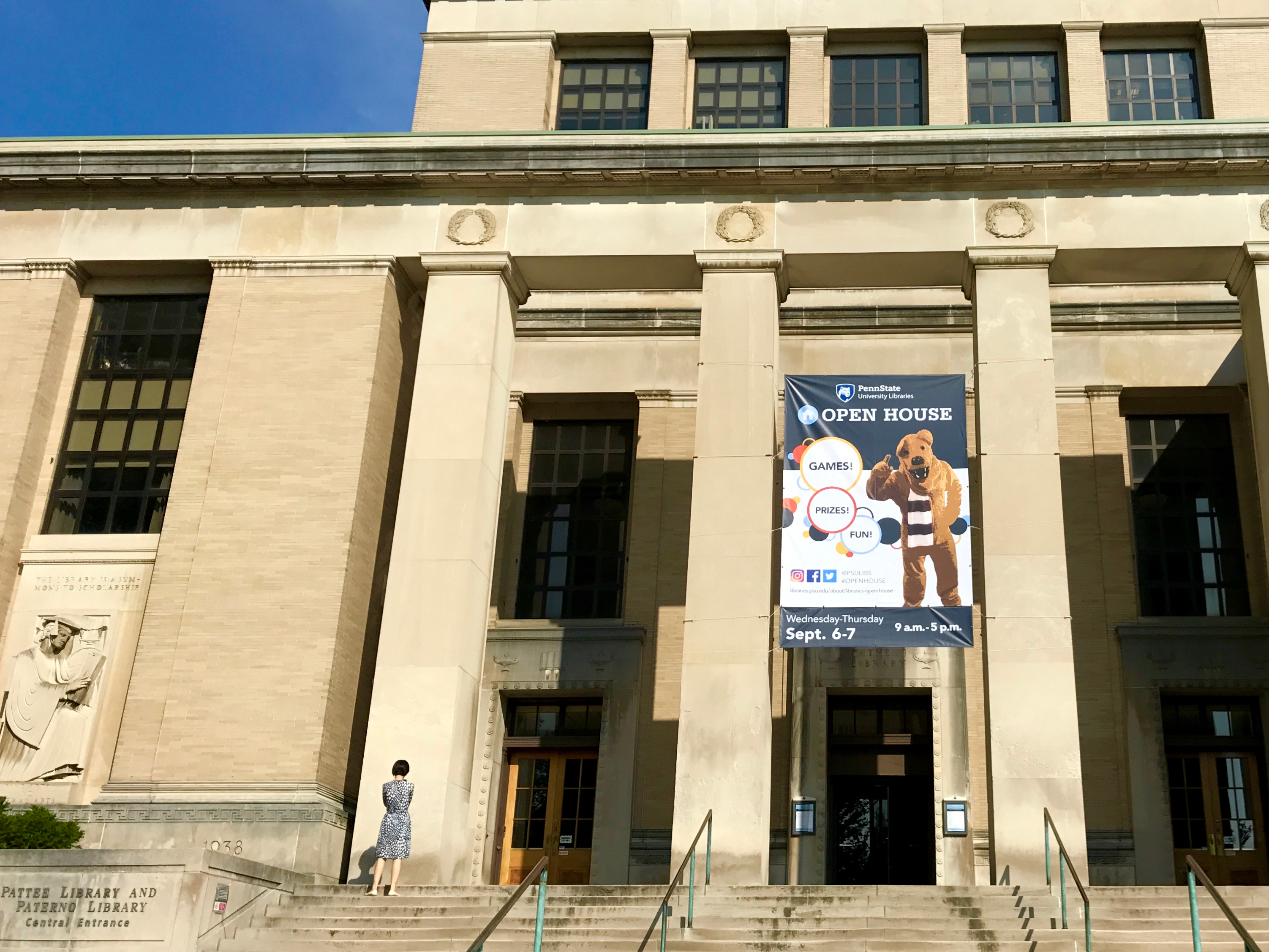 horizontal exterior photo of Pattee Library and Paterno Library with open house banner hung between concrete pillars