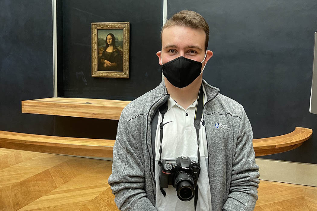 Sebastien Kraft standing in the Louvre with the Mona Lisa in the background.