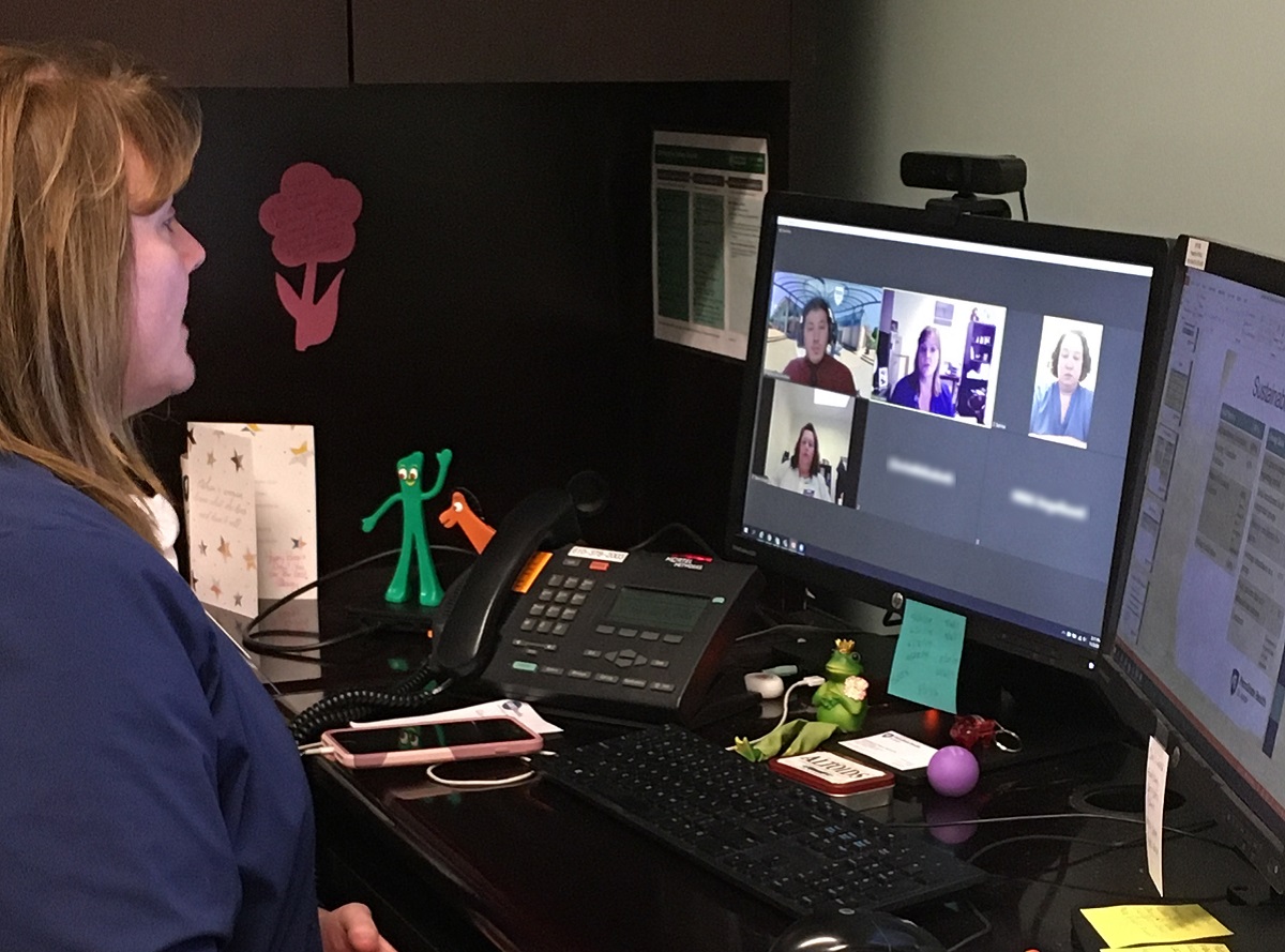 Director of women’s and children’s services Kirsten Hakim looks at her computer monitor, as she participates in an online career readiness session. There is a black keyboard, black phone and pink mobile phone on the desk in front of her.