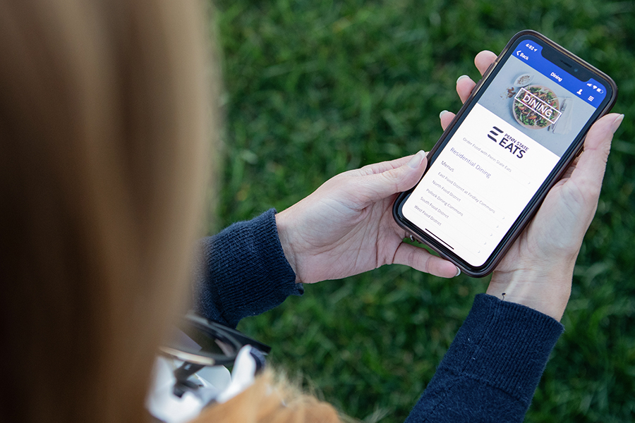 A female student uses the Penn State Dining app on her smartphone