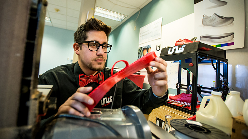 Nicholas Unis inspects a piece of his 3D-printed custom sneaker.