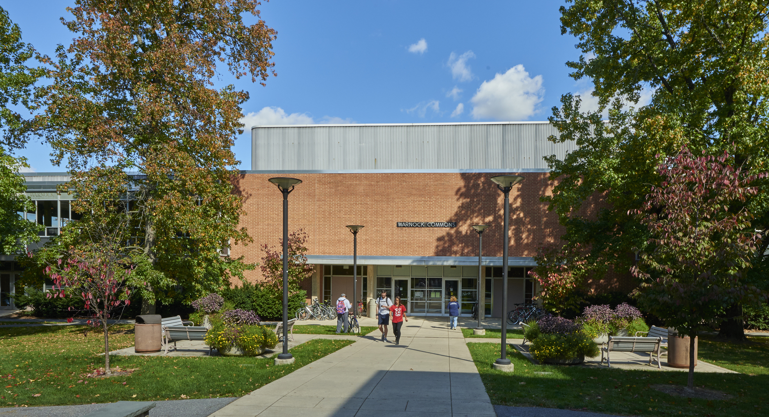 Students walking outside of Warnock Commons on a fall afternoon. 