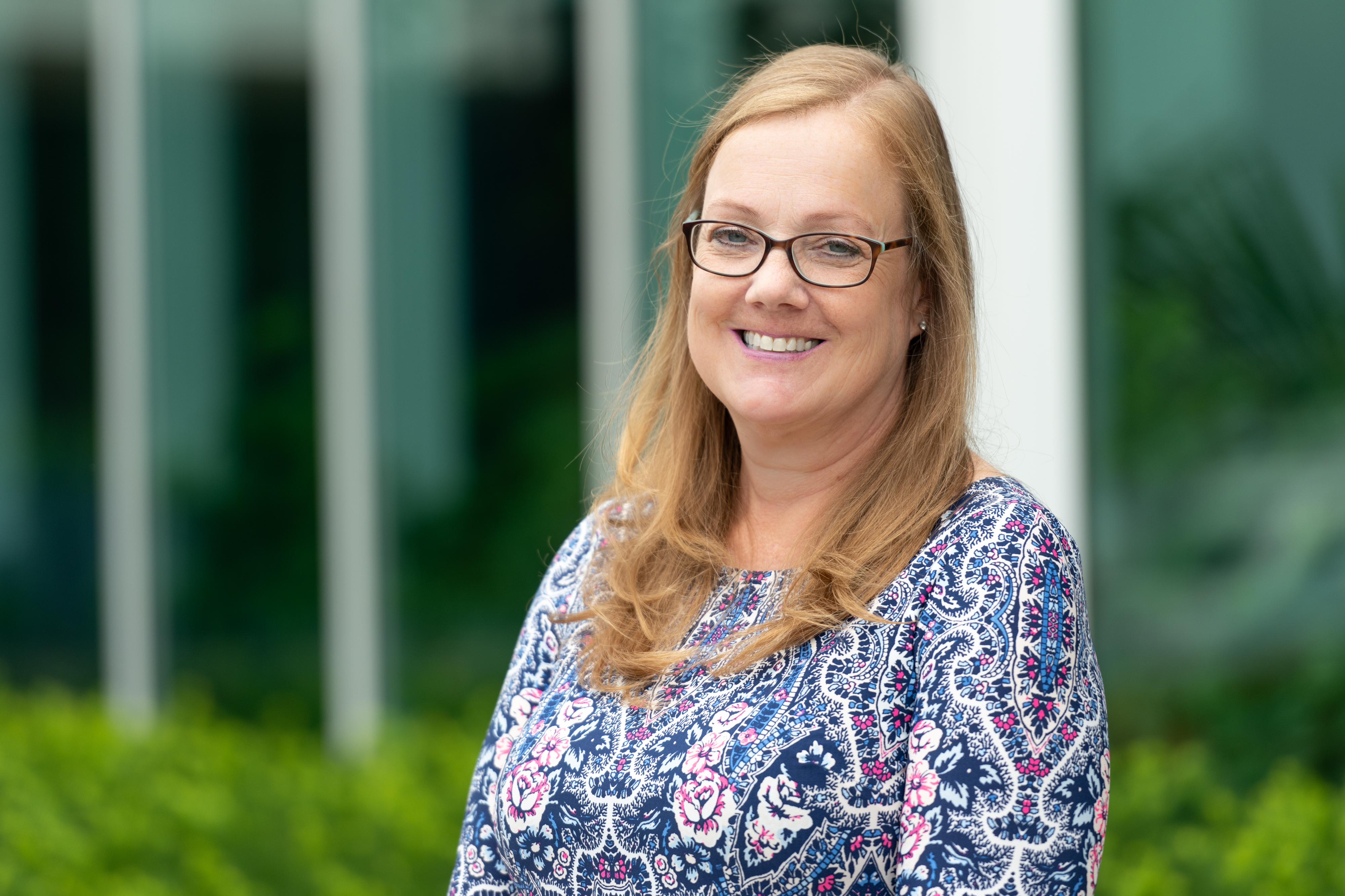 head shot of woman wearing glasses outside office building