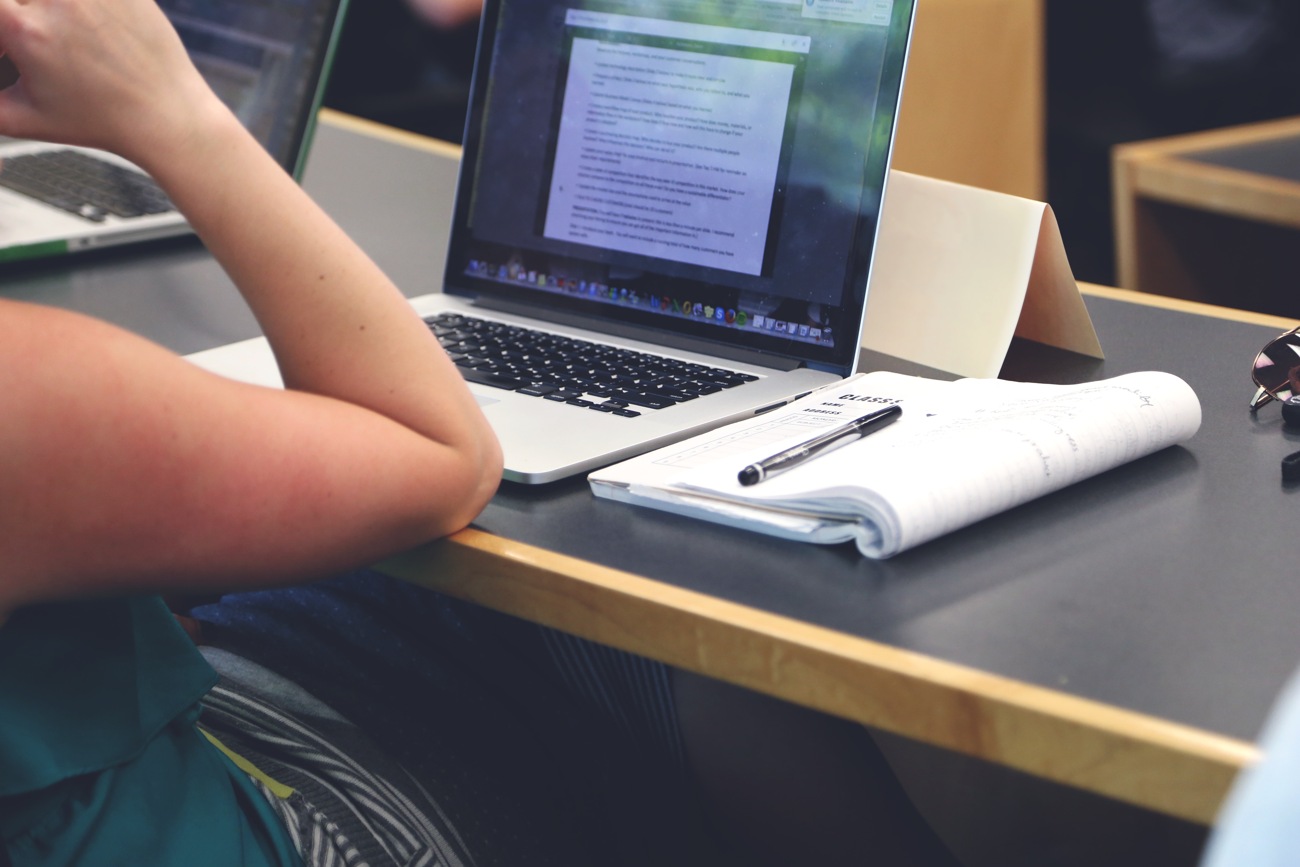 Person in classroom with laptop and notepad