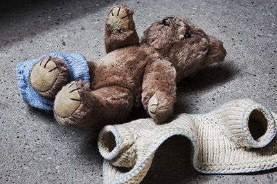 teddy bear with half on pants and sweater laying next to it.