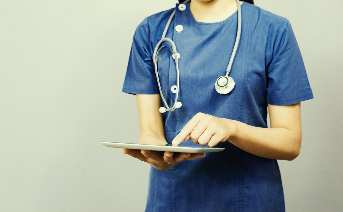 A female doctor enters data onto an iPad as part of a patient's electronic health record