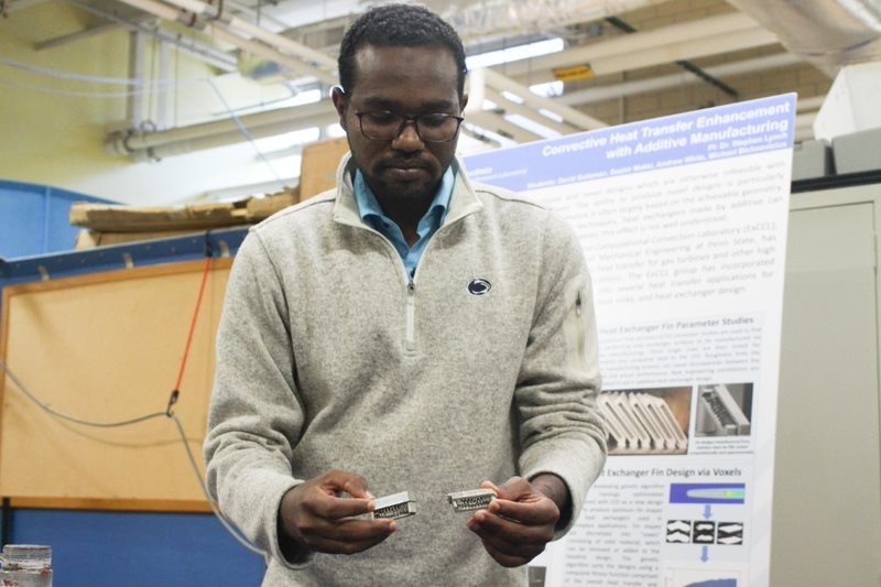 A Sudanese man holds small piece of metal in a lab. 