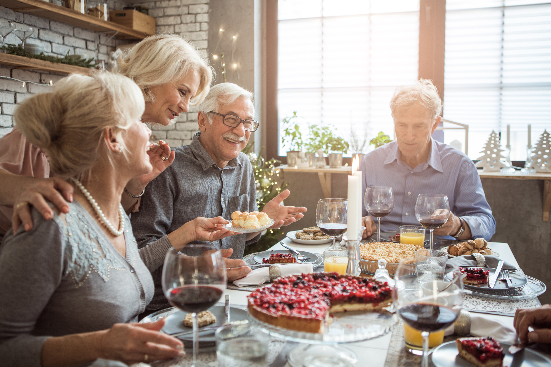 A group of older adults sitting around a table talking and smiling