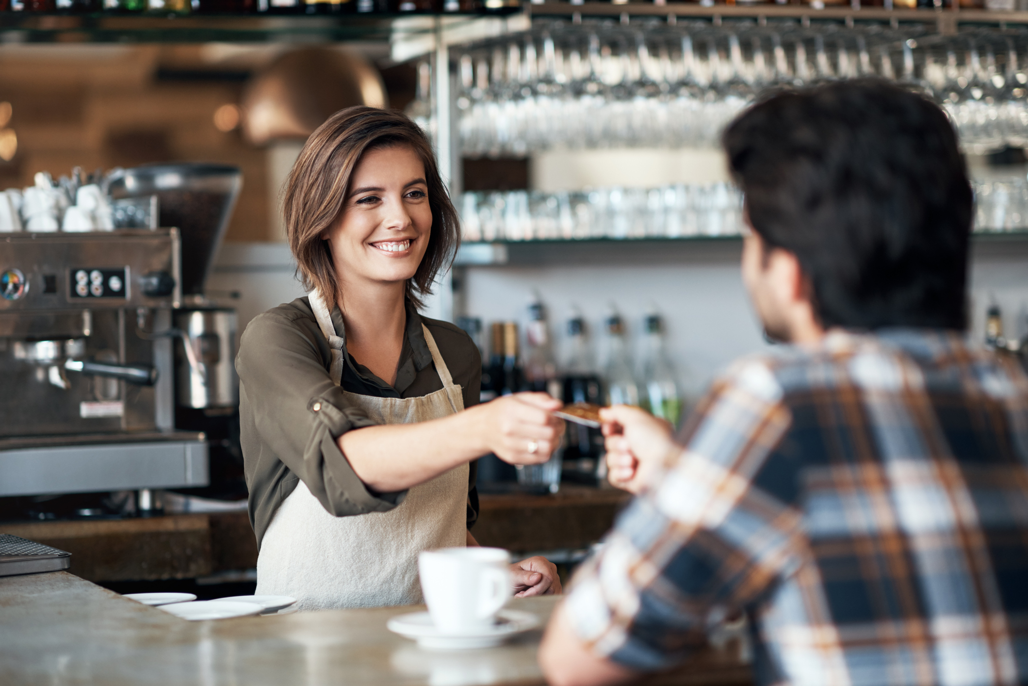 A smiling waitress or barista handing a card back to a customer