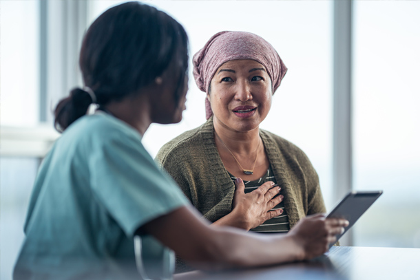 A nurse and a patient talk at a table.