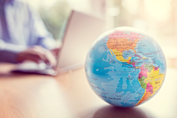 person using laptop in background with a close up of a globe in the front