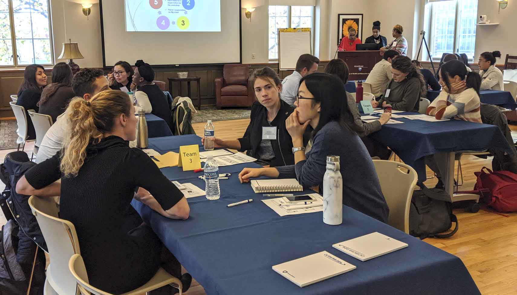 workshop participants at tables discussing an icebreaker activity