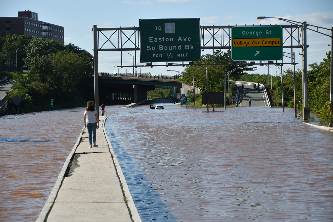 woman walks on median surrounded by flooding after Hurricane Ida