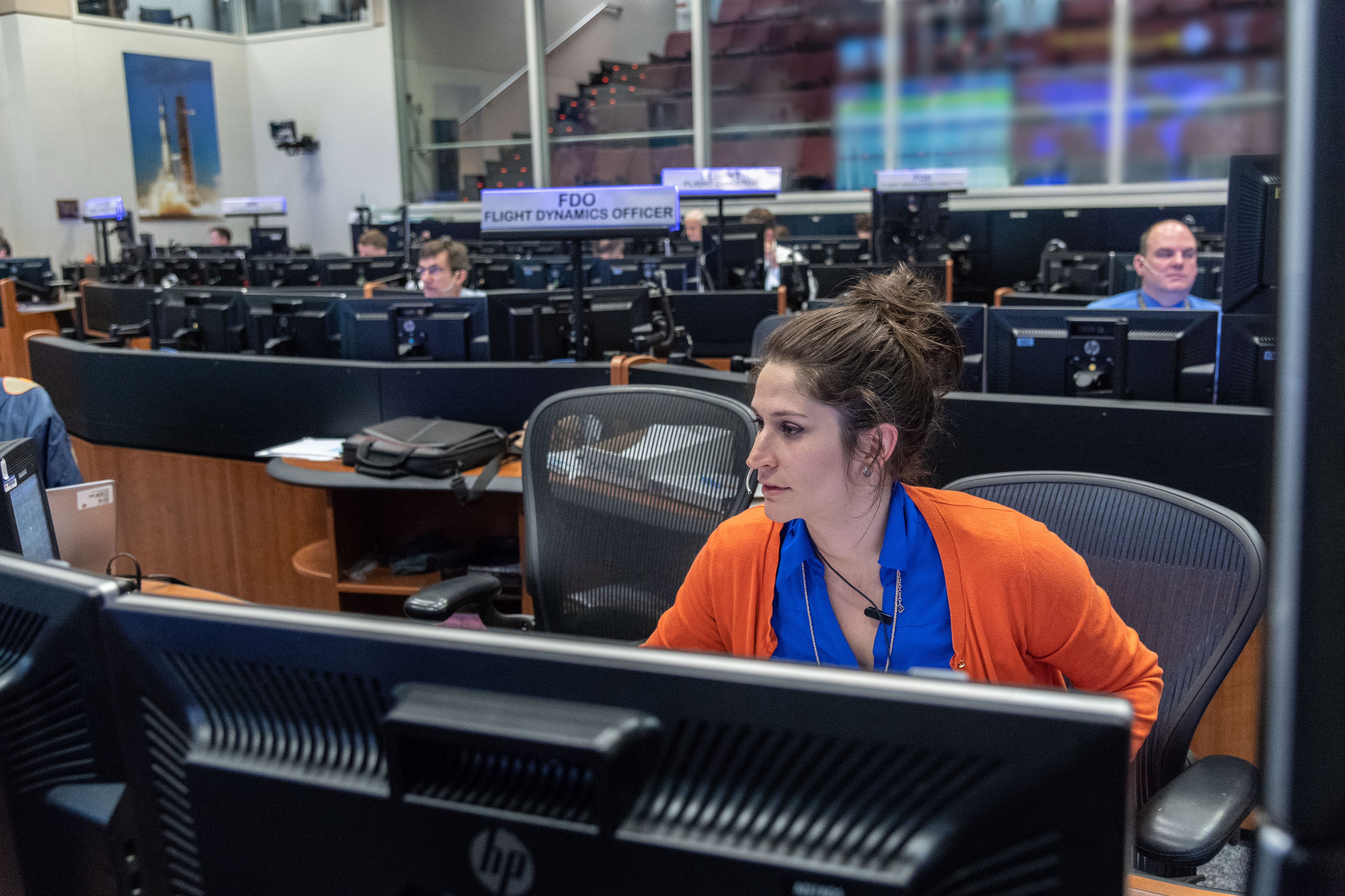 a person sits at a computer console in a control room.