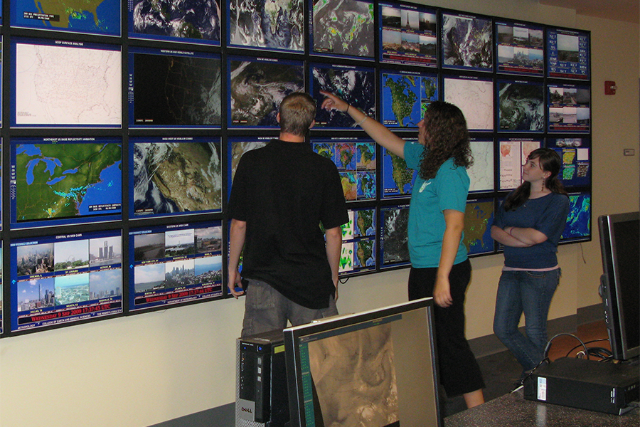 meteorology students stand at Joel Myers weather wall