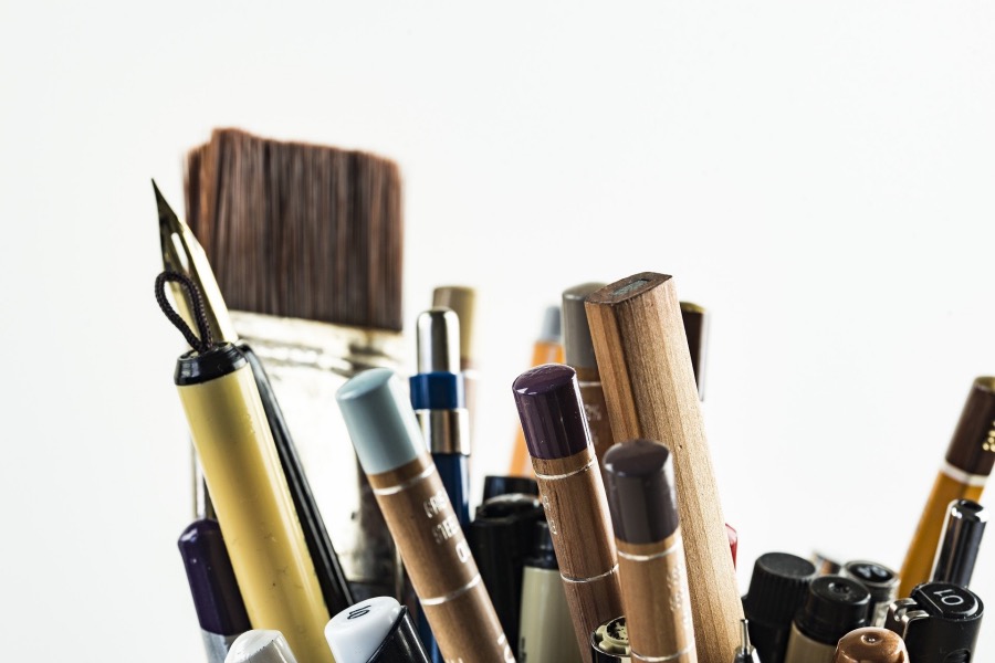 A photo shows paintbrushes, a calligraphy pen and pencils.