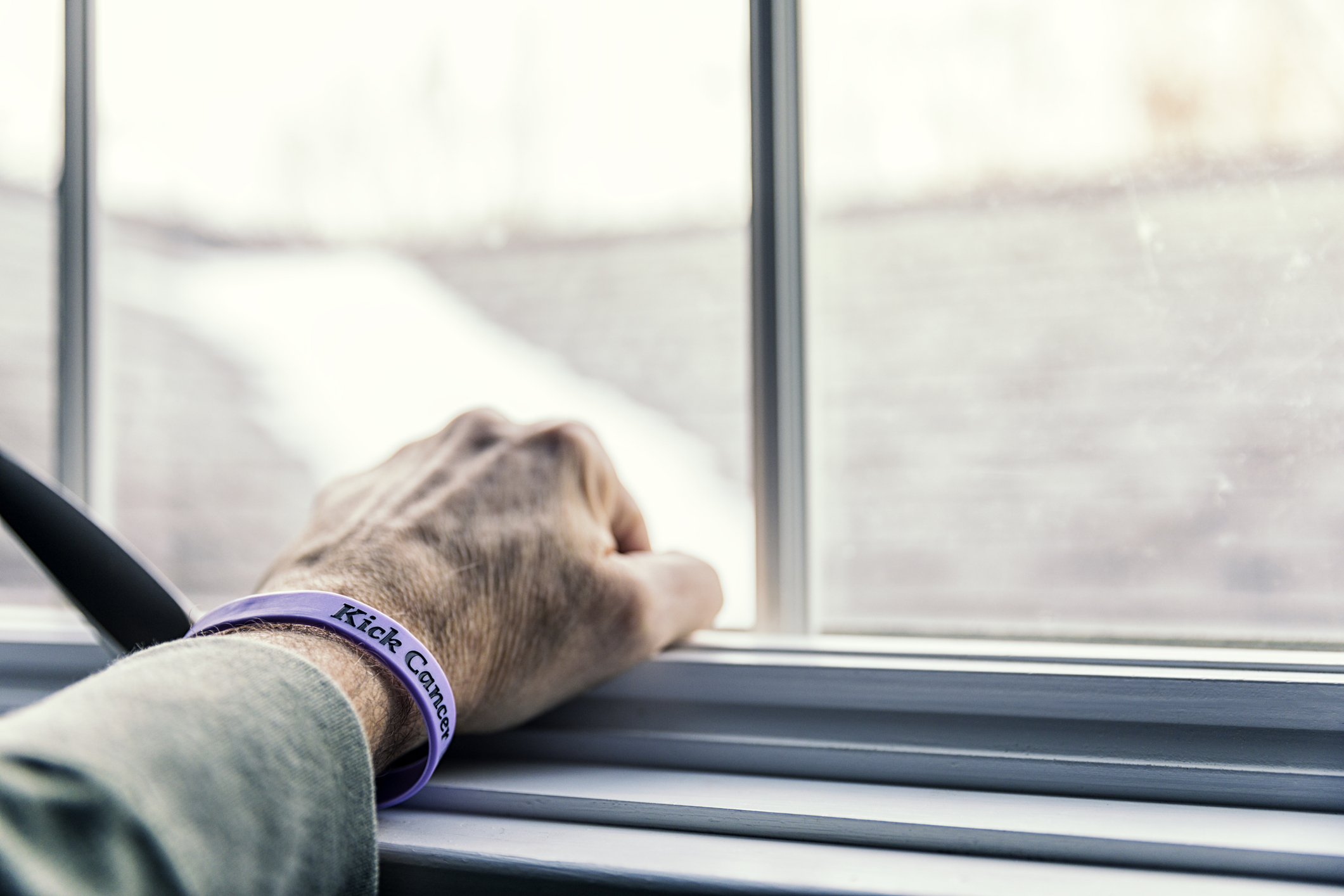 The hand of an elderly patient resting on a windowsill