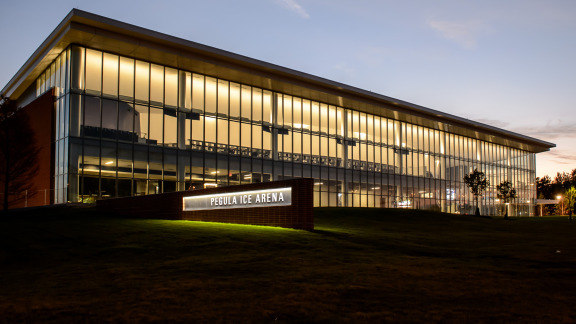 Pegula Ice Arena with lights on at dusk