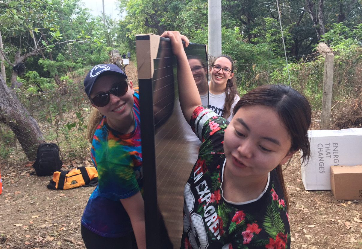 students carrying solar panel