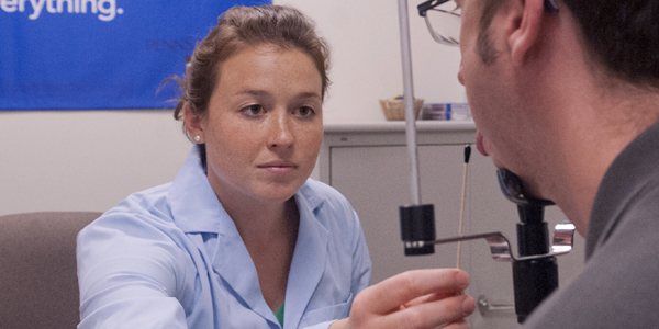 woman in lab coat swabbing a man's tongue