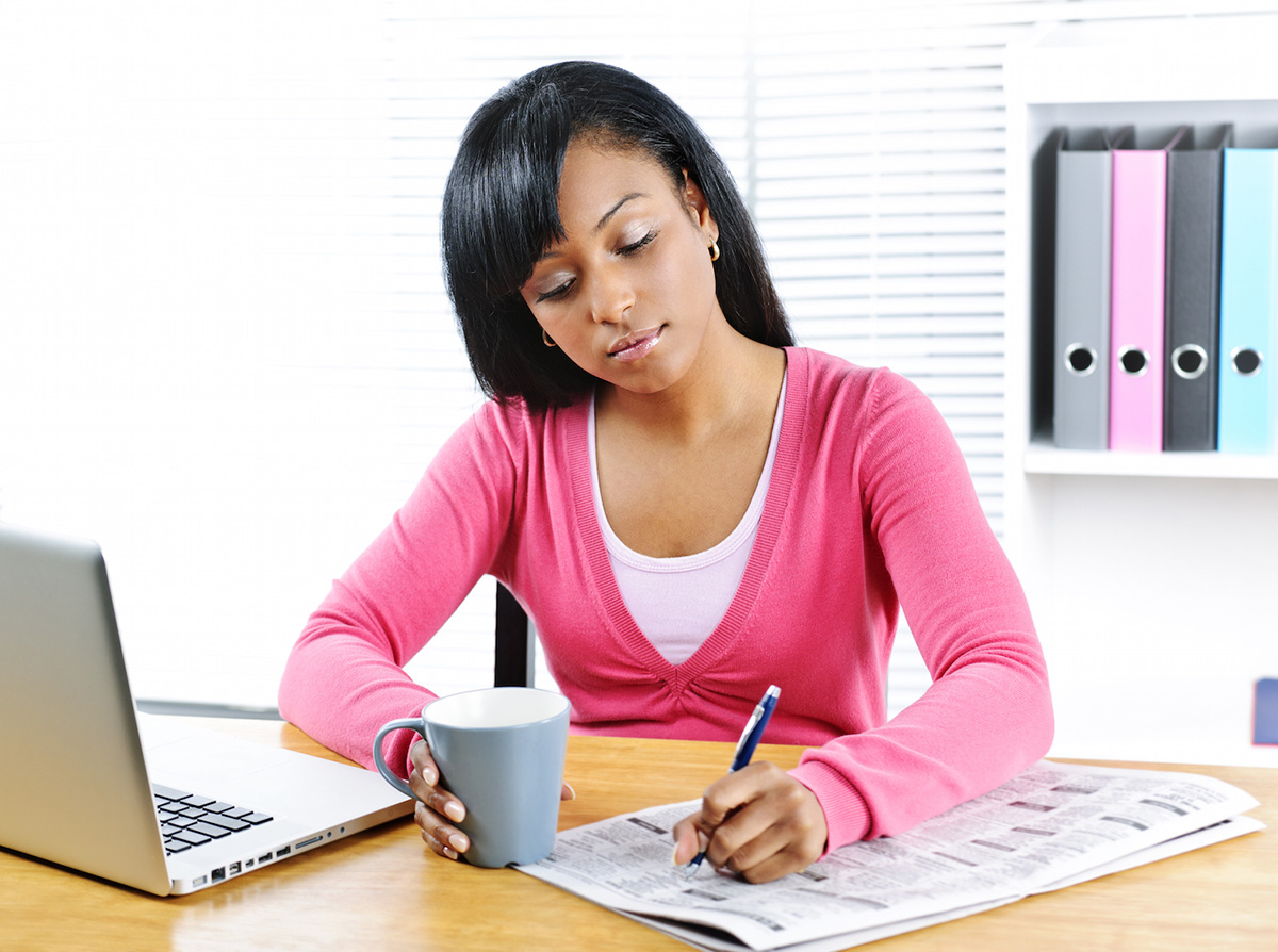 Young black female student looking in newspaper for job