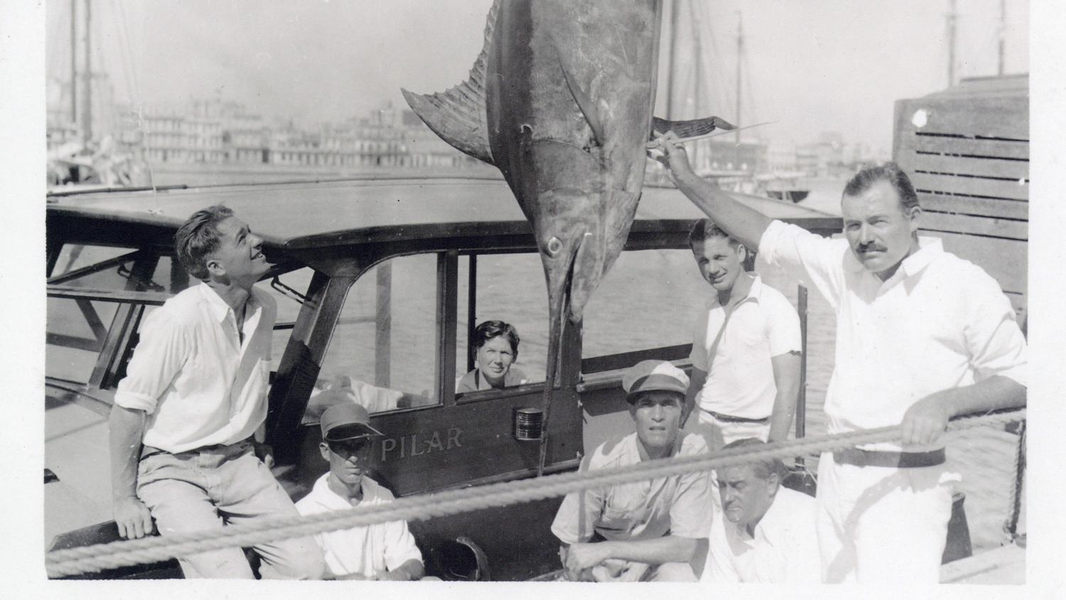 Picture of people on a boat admiring a large fish. 