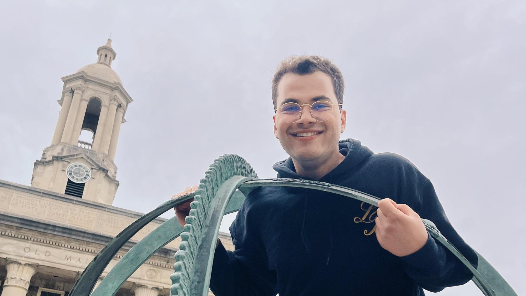Najee Rodriguez stands on the armillary sphere in front of Old Main