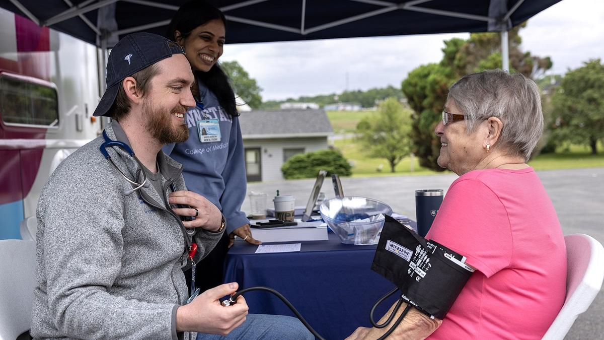 A medical student gives a woman a blood pressure screening.