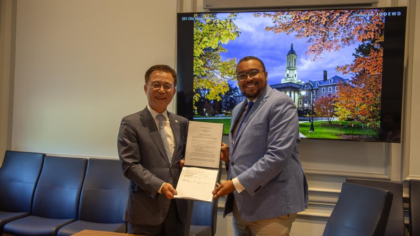 Two men holding a piece of paper and smiling