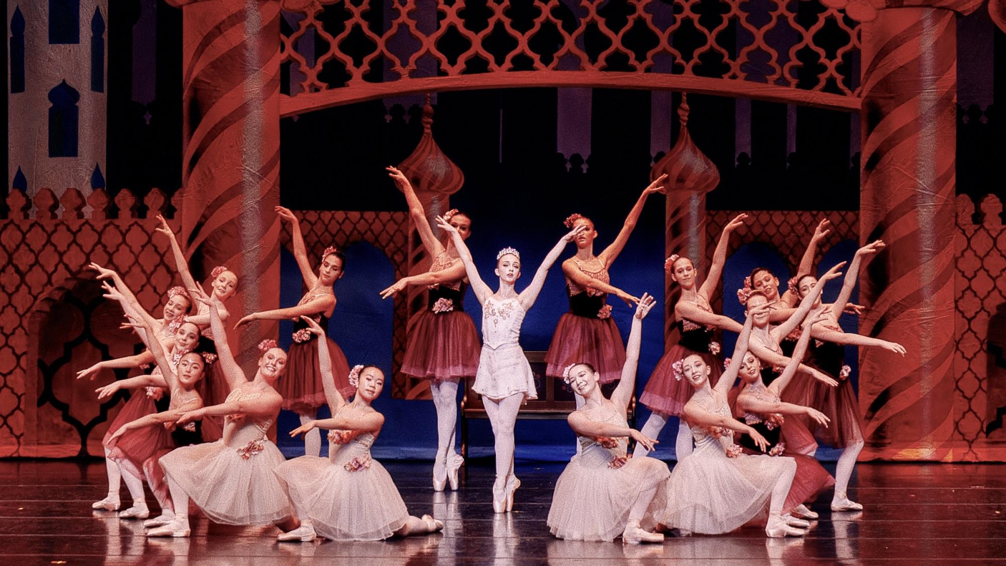 A group of young ballet dancers stand in formal poses.