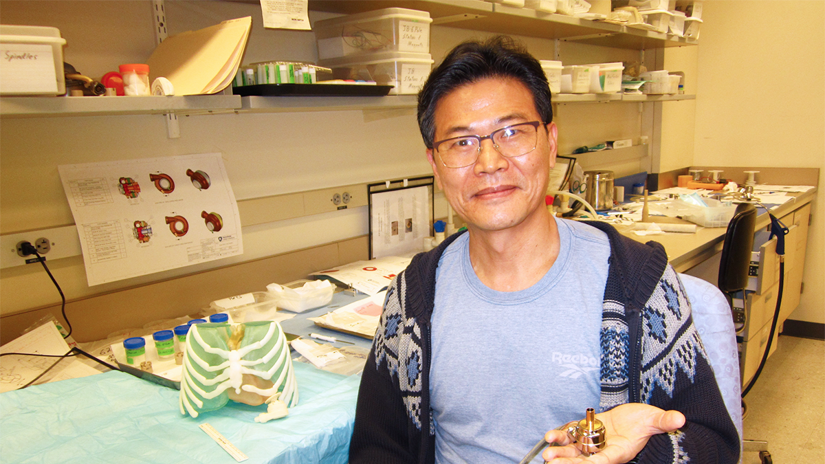 Scientist sitting in a lab and holding a prototype of a heart pump