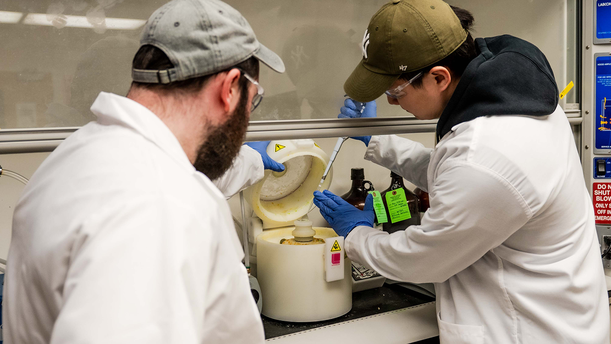 Dor Tillinger, doctoral candidate of mechanical engineering, and Donbae Lee, doctoral candidate of engineering science and mechanics, dressed in lab coats using lab equipment.