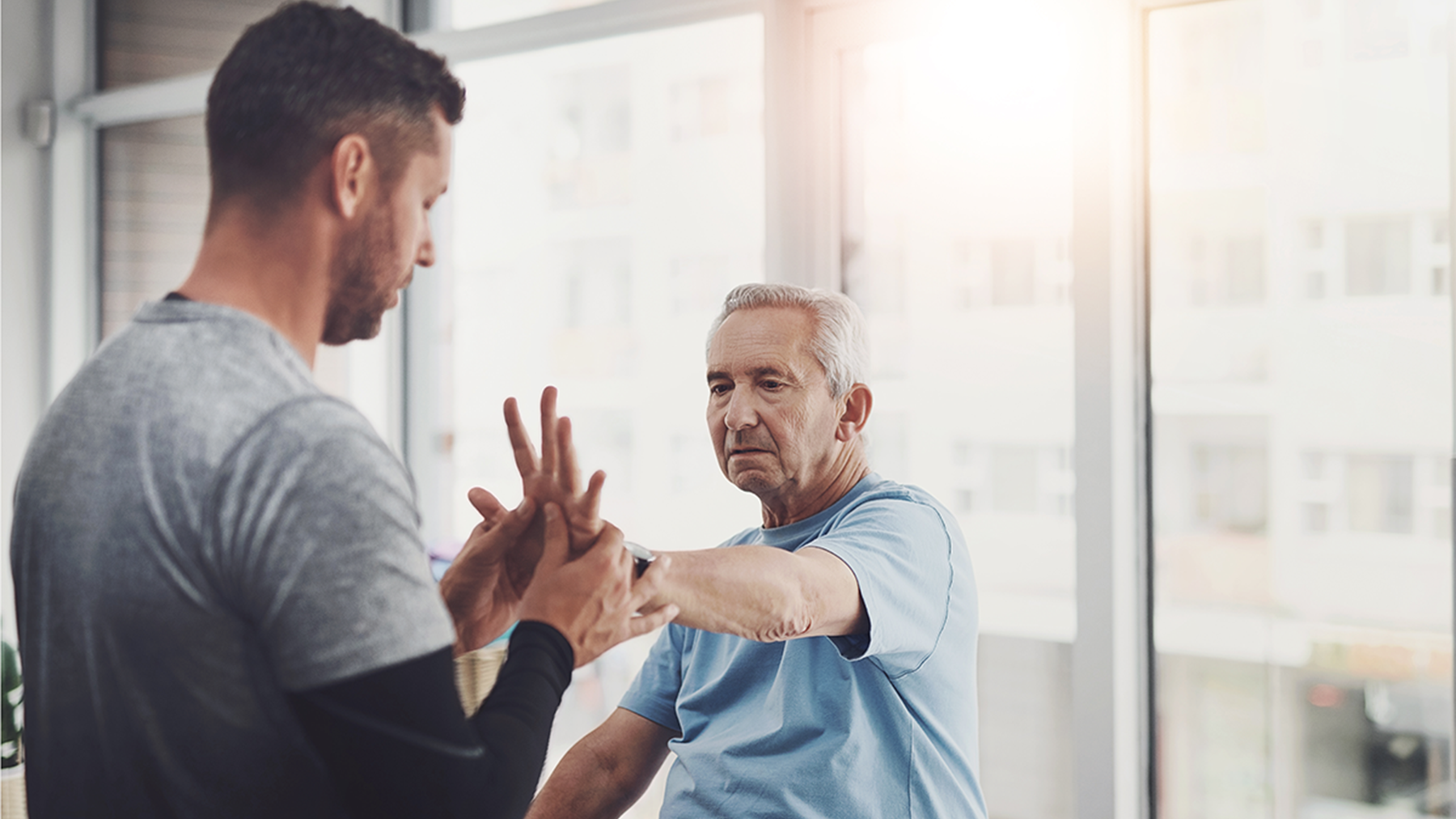 Older man doing hand therapy exercises with a physical therapist