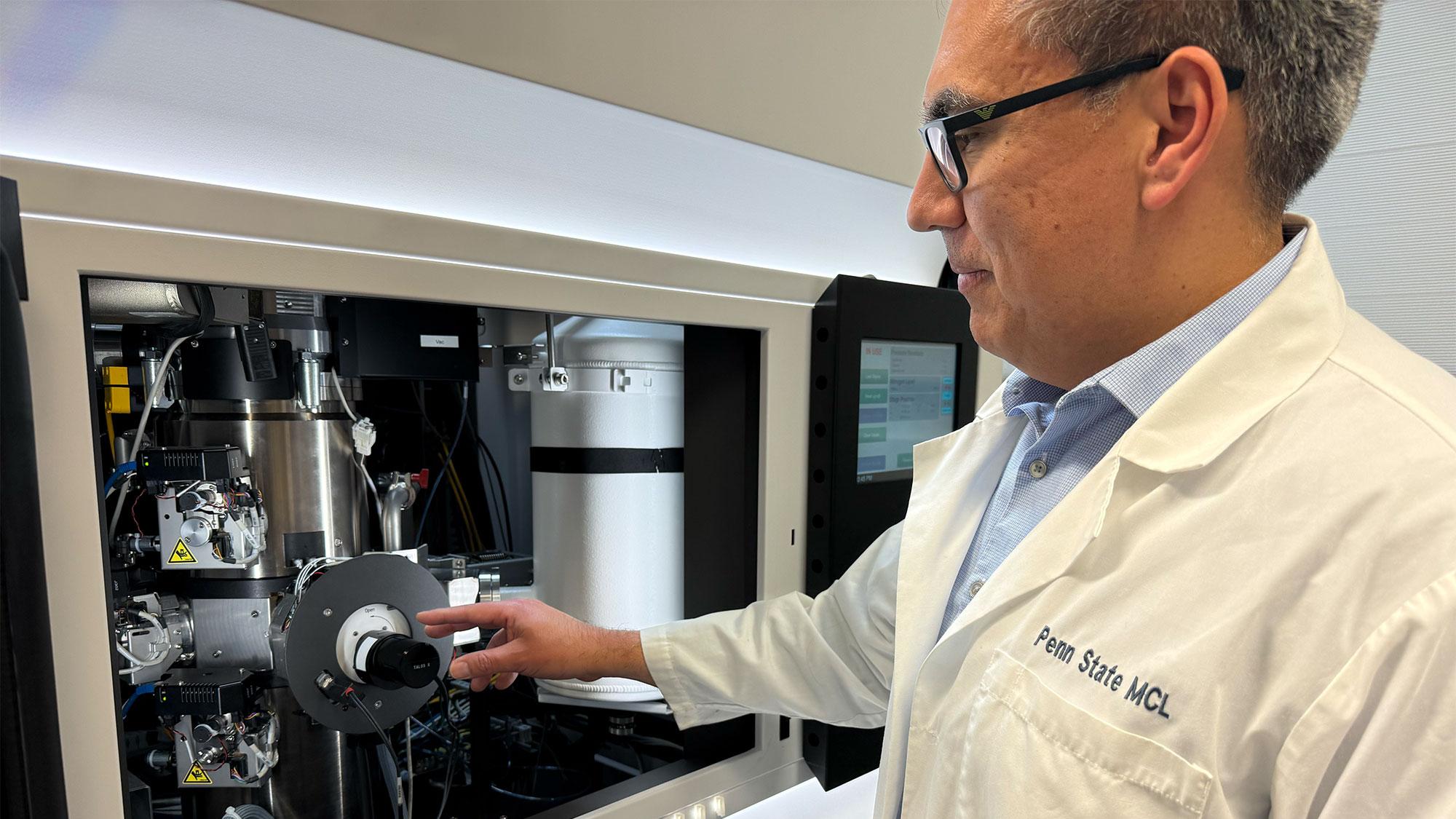 Enrique Gomez stands in a lab testing a sample in a cyrogenic-electron microscope
