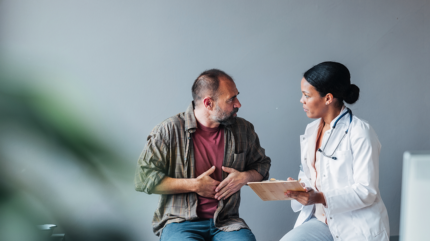 Person gesturing to their stomach and speaking with a doctor