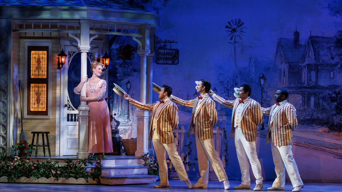 Four men in striped jackets serenade a woman on a porch.