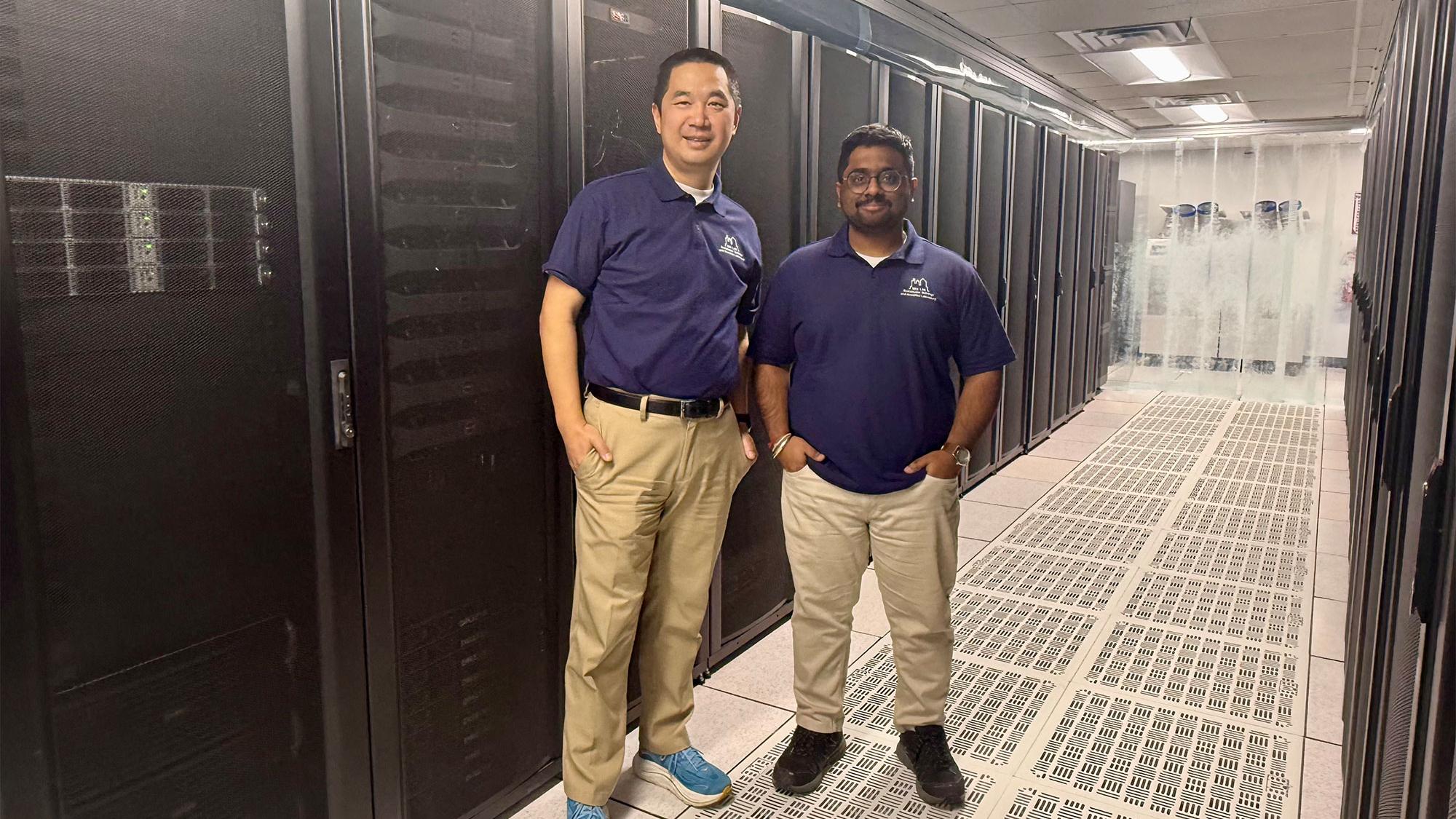 Two researchers at Penn State pose together in front of tall machinery and server racks in a data center