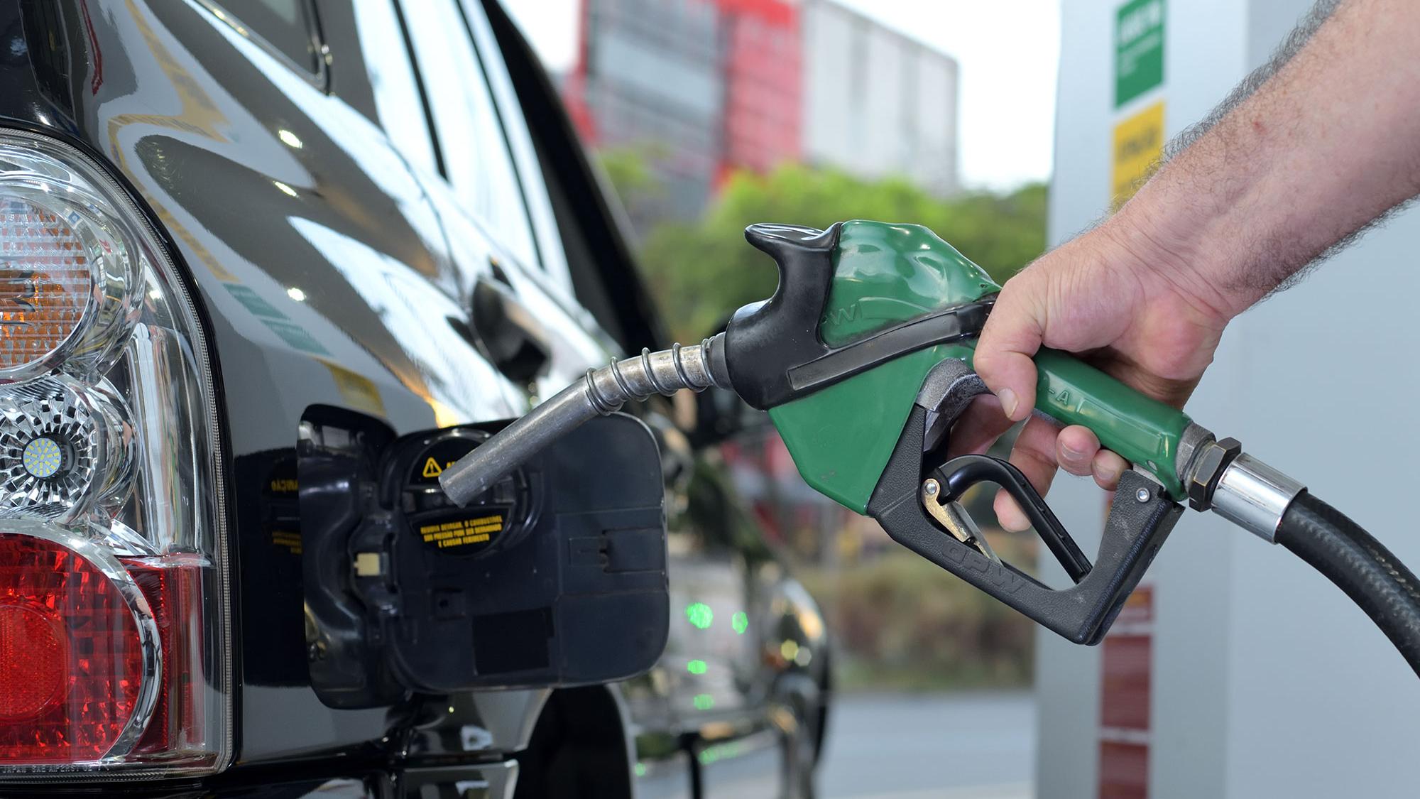 The picture shows a hand holidng a gas pump and pumping gas into a car.