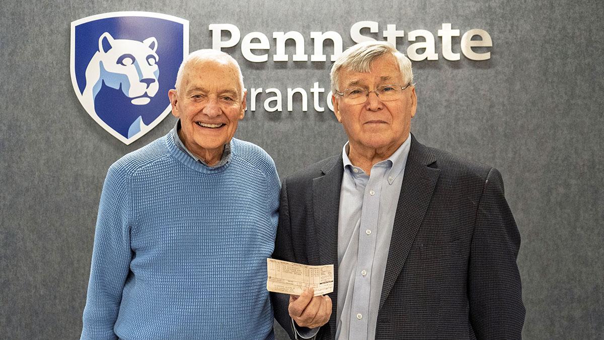 Mike Abdalla and Joe clifford pose for a photo, showing one of Clifford's old grade reports