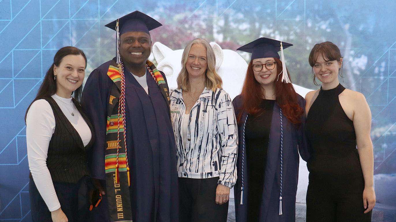 Five people pose in front of a Penn State photo background.