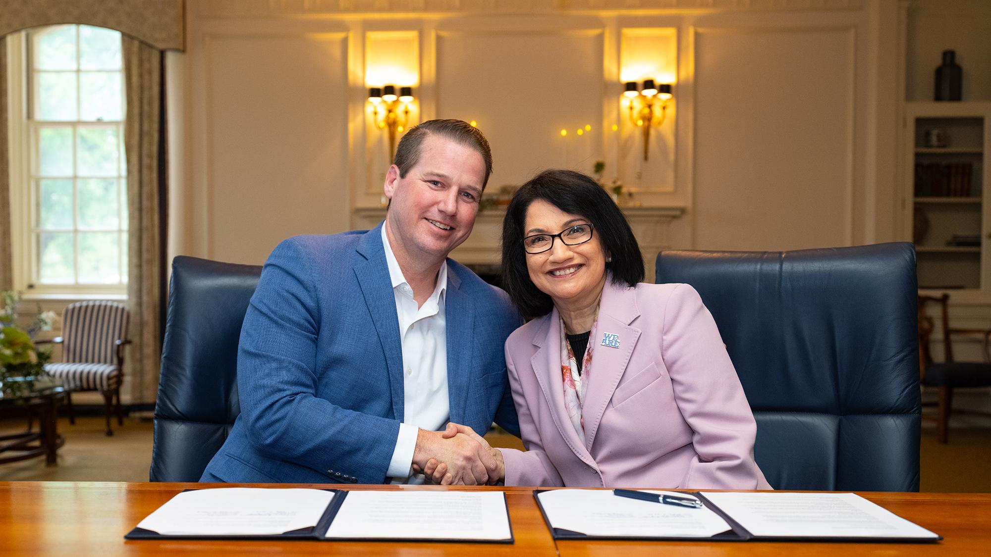 Two people sitting at a table shake hands